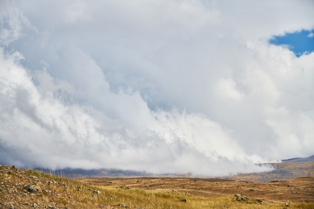 Nuvens sobre os espaços abertos das estepes, nuvens de tempestade sobre as colinas. O Planalto De Ukok No Altai. Paisagens frias fabulosas. Alguém por perto