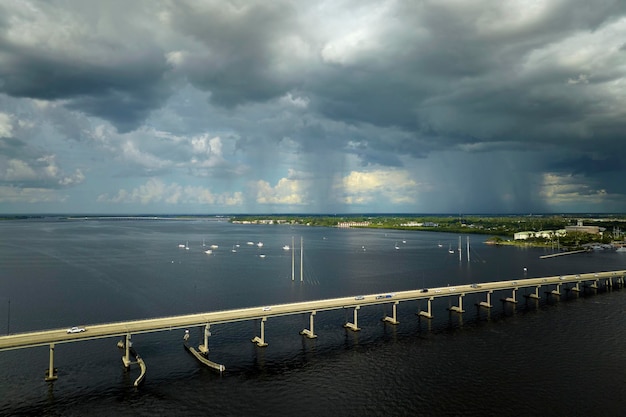 Nuvens tempestuosas formadas pela evaporação da umidade da água do oceano antes da tempestade sobre a ponte de tráfego que liga Punta Gorda e Port Charlotte sobre o rio Peace Condições climáticas ruins para a condução