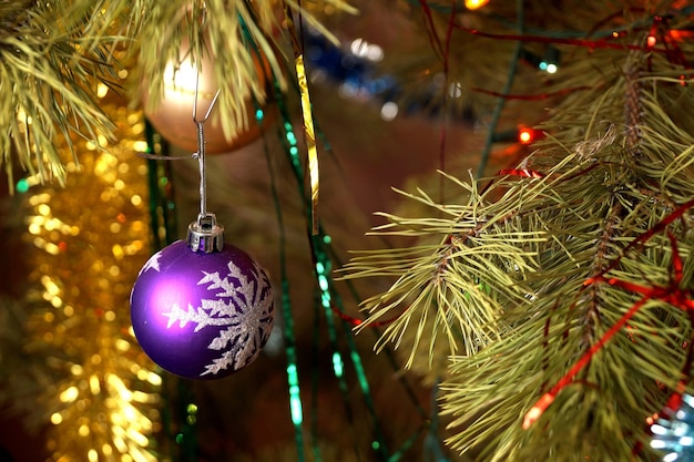 O abeto brinca com uma esfera de plástico com o floco de neve desenhado