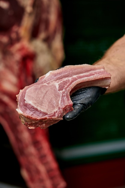 Foto o açougueiro segura um pedaço de lombo de porco