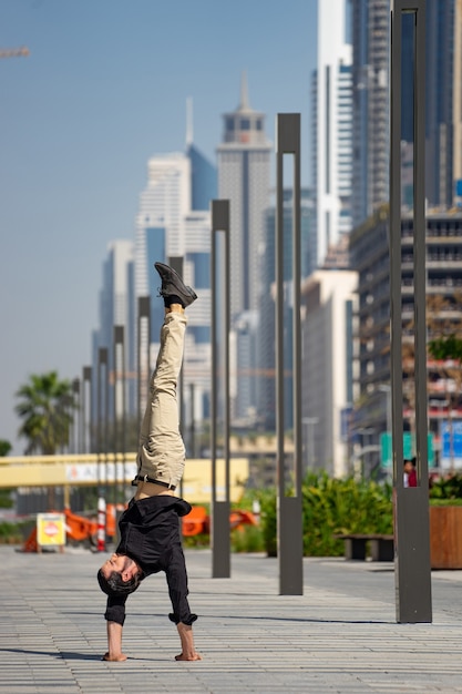 Foto o acrobat mantém o equilíbrio entre as mãos com a paisagem urbana borrada de dubai. conceito de modernidade, negócios e possibilidades ilimitadas.