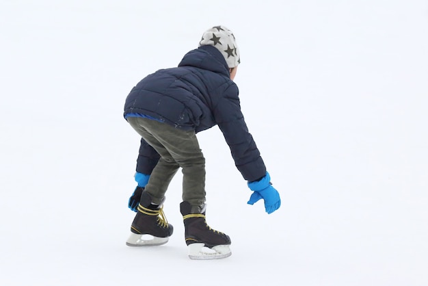 O adolescente está patinando na pista de gelo