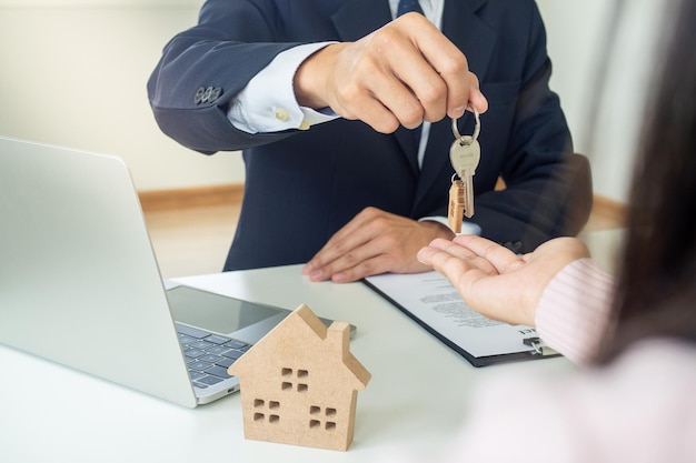 O agente imobiliário detém as chaves da casa enviando as mãos dos clientes após a celebração de um contrato de compra de seguros ou de recuperação de bens imóveis ou imóveis.