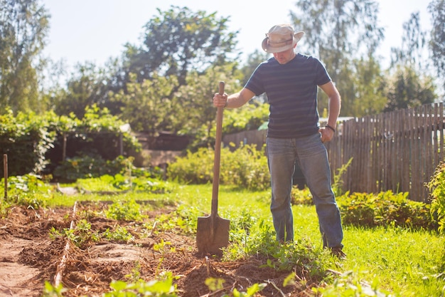 Foto o agricultor fica com uma pá no jardim preparando o solo para o plantio de vegetais conceito de jardinagem trabalho agrícola na plantação
