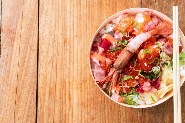 O alimento japonês do chirashi saboroso e delicioso na tabela de madeira, comer saudável e come bem o conceito. Leve comida para casa. Vista superior, espaço de cópia