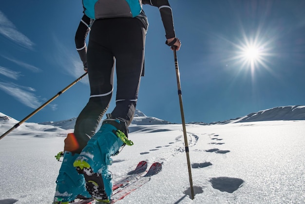 O alpinista de esqui sobe uma encosta nevada com peles de foca