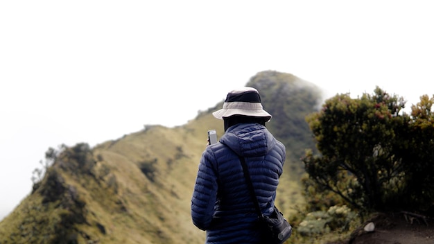 O alpinista está documentando a vista do monte merbabu com seu smartphone