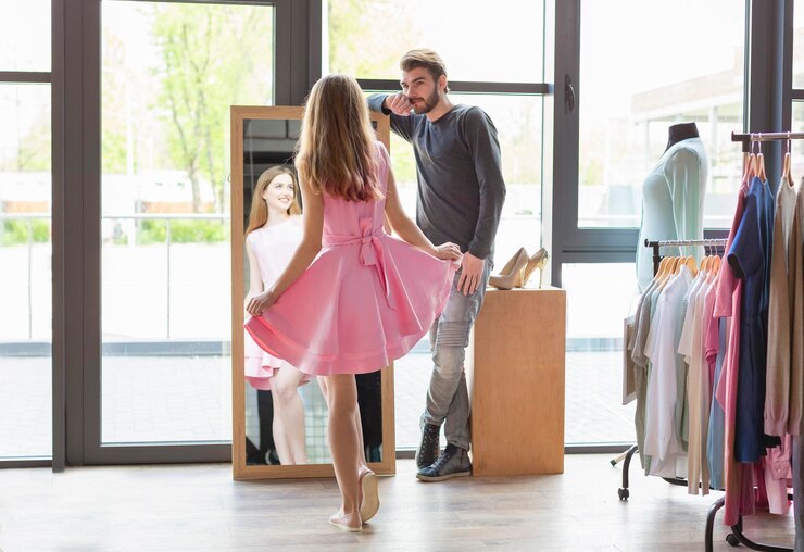 Foto o amor está no ar. cara caucasiano atraente olhando para sua mulher, garota está experimentando vestido rosa na boutique, olhando para o espelho