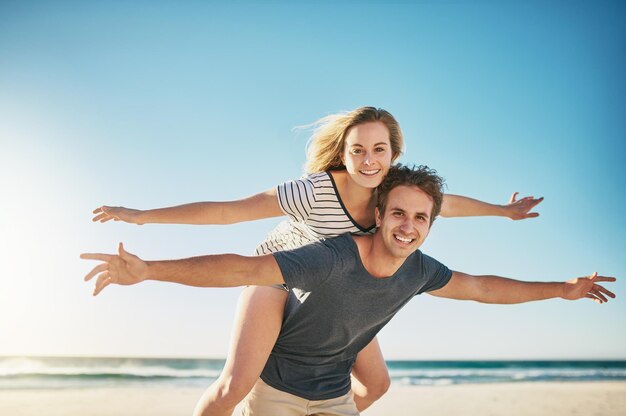 O amor nos faz sentir vivos Foto de um jovem casal feliz curtindo um passeio nas costas na praia