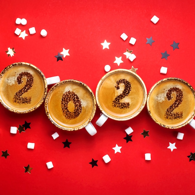 O ano novo é desenhado em xícaras de café sobre fundo vermelho
