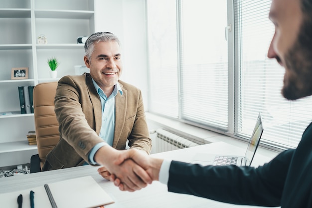 O aperto de mão dos empresários acima da mesa do escritório