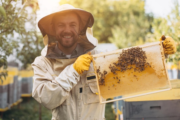 O apicultor segura uma célula de mel com abelhas nas mãos Apicultura Apiário Abelhas de trabalho em favo de mel Favo de mel com mel e abelhas closeup