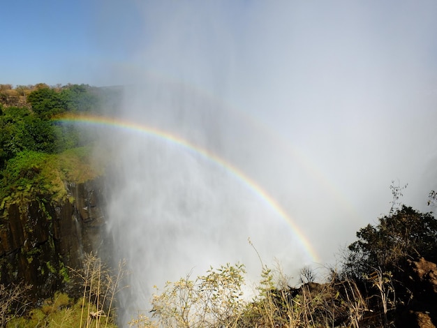 O arco-íris em Victoria Falls na fronteira Zâmbia e Zimbábue