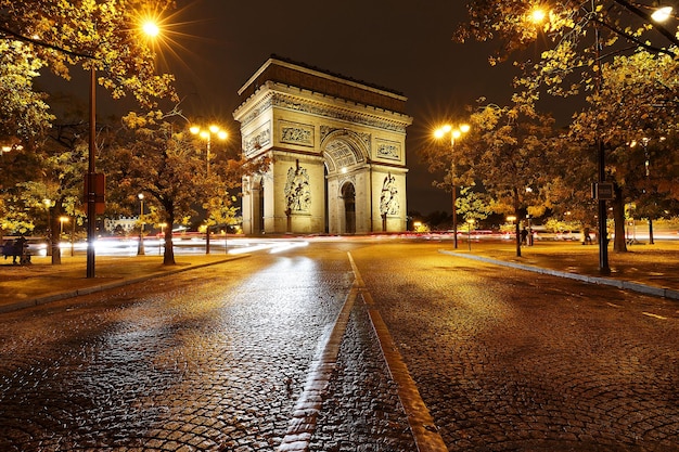 O arco triunfal na noite chuvosa Paris França