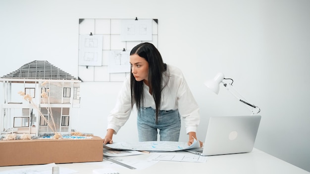 O arquiteto coloca o plano na mesa e compara com o modelo da casa Immaculate