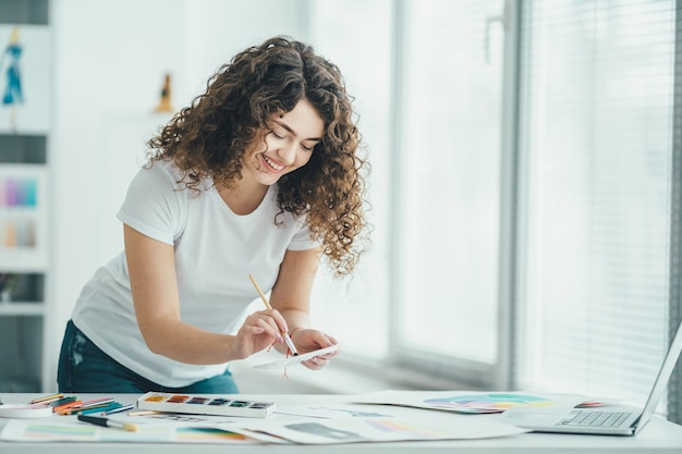 O artista encaracolado pintando um quadro na mesa