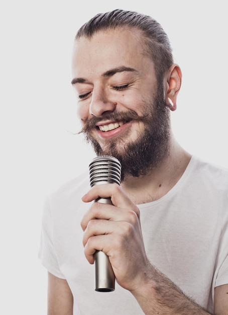 O artista jovem falante segurando o microfone isolado no fundo branco