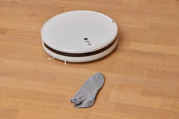 O aspirador robótico realiza a limpeza da sala onde as meias estão no chão Tecnologia de limpeza inteligente