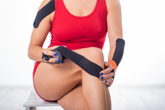 O atleta coloca uma fita médica no joelho tratamento alternativo para lesões nas articulações e tendões Fisioterapia da inflamação crônica das articulações da perna feminina