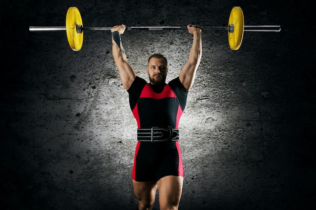 Foto o atleta está em pé com uma barra acima da cabeça. vista frontal