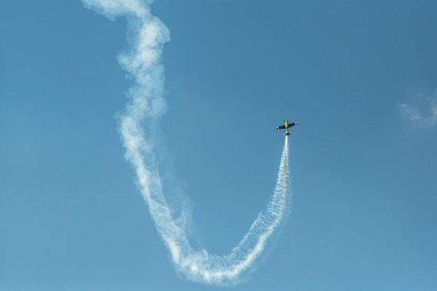 O avião acrobático com trilha de fumaça no céu