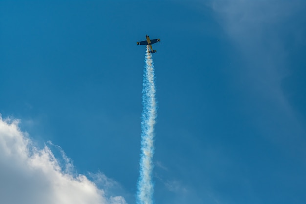 O avião acrobático com trilha de fumaça no céu