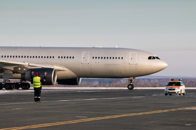 O avião de passageiros está se movendo atrás do carro siga-me. Tripulação de solo do aeroporto encontra aeronave