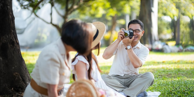 O avô tira fotos da neta e da avó com ele no parque em um dia ensolarado conceito de felicidade avô e neta família vive juntos felizes