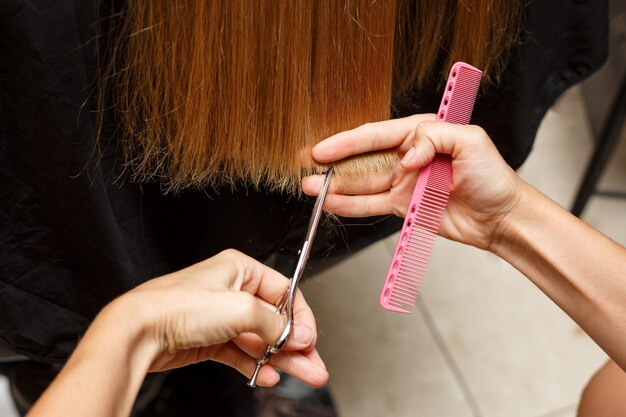 O barbeiro corta o cabelo do cliente.