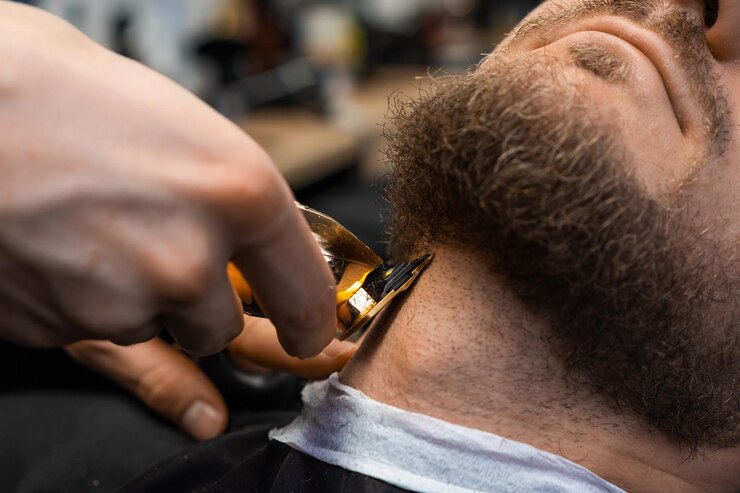 Foto o barbeiro corta rapidamente a barba do cliente com um cortador automático na barbearia