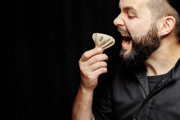 O barbudo está comendo khinkali emocionalmente. O prato nacional georgiano khinkali. Conceito de fotografia publicitária de khinkali.