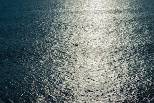 O barco navega ao pôr do sol no oceano.