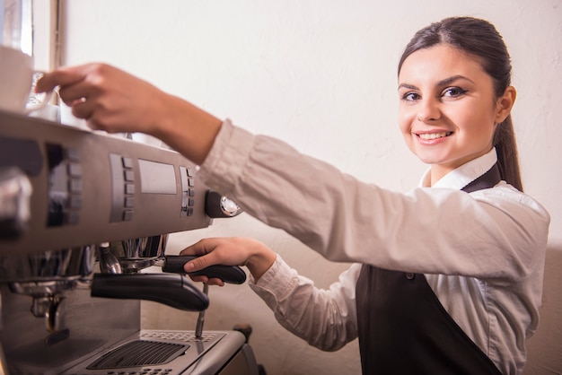 O barista fêmea de sorriso está preparando o café na cafetaria.