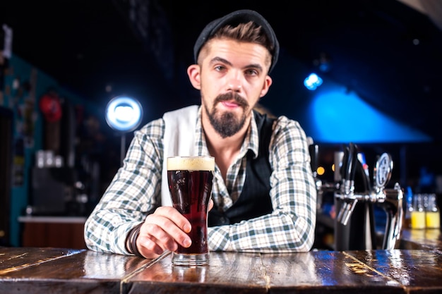 O barman barbudo cria um coquetel em pé perto do balcão do bar