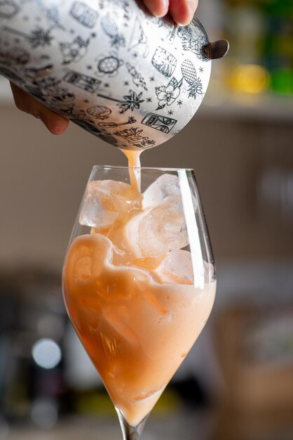 O barman está preparando um coquetel no bar A mão do barman está servindo um coquetel pronto em um copo