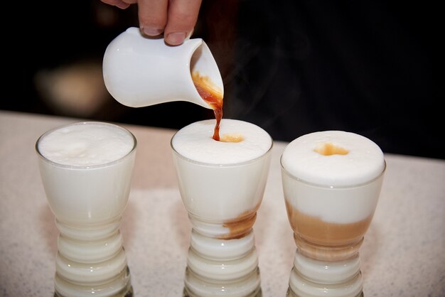 O barman está preparando uma bebida de café quente.