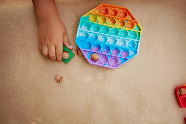 O bebê brinca com o brinquedo sensorial anti-stress colorido, empurre-o para o desenvolvimento de habilidades motoras