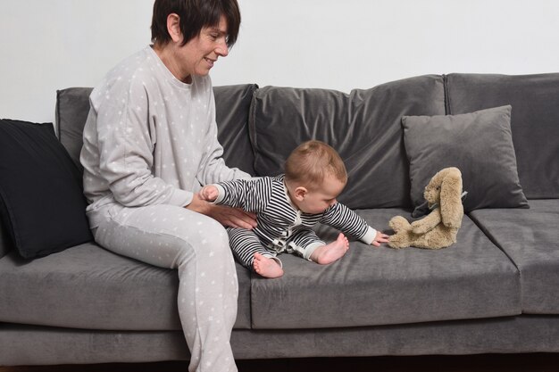 O bebê com a mãe sentada no sofá o bebê quer levar a boneca