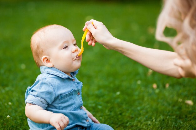 O bebê come com uma colher no parque