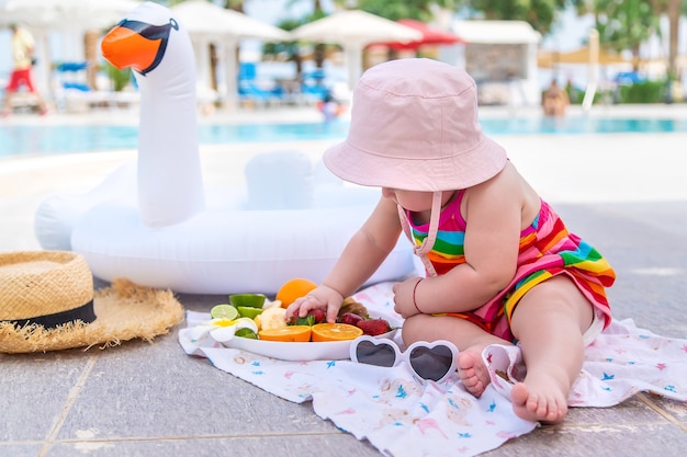 O bebê come frutas nas férias. Comida.