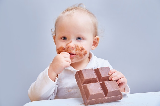 O bebê come uma grande barra de chocolate