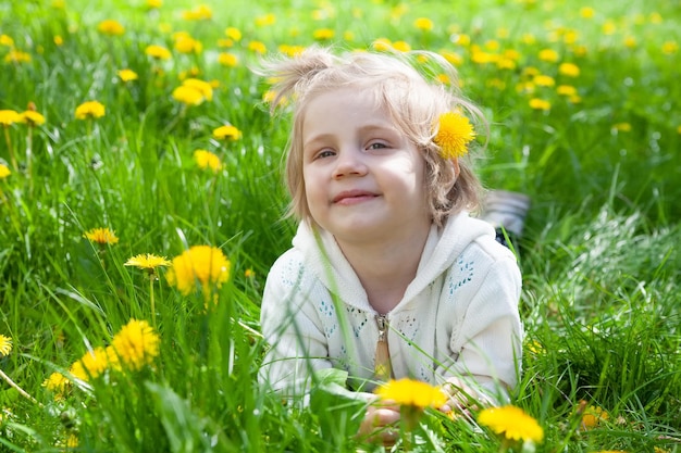 O bebê encontra-se no prado com dentes de leão