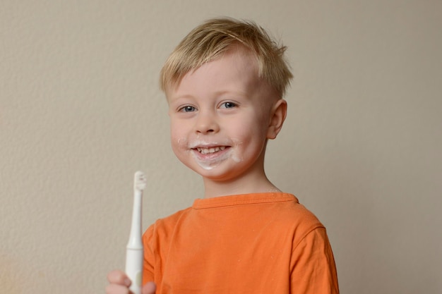 O bebê escova os dentes com uma escova elétrica