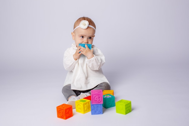 O bebê está brincando com cubos coloridos em um fundo branco