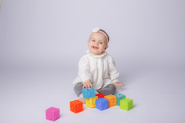 O bebê está brincando com cubos coloridos em um fundo branco