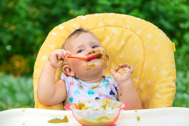 O bebê está comendo purê de vegetais. Foco seletivo. Filho.