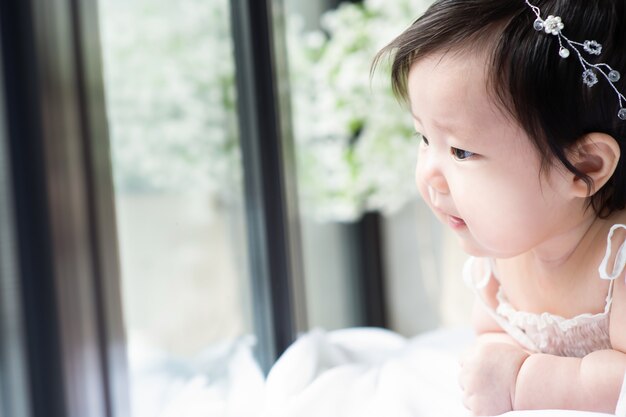 O bebê está deitado e sorrindo olhando pela janela