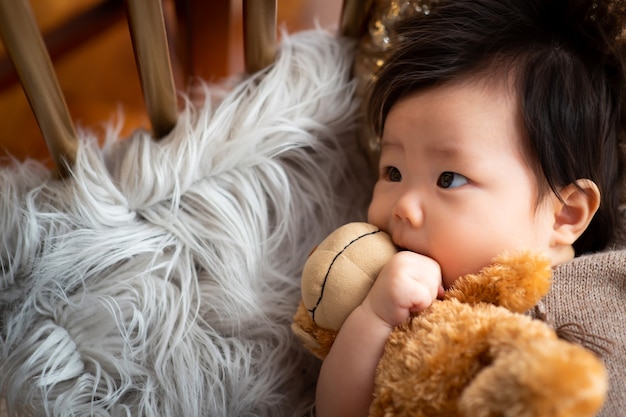 O bebê está deitado no tapete e sentado na boneca