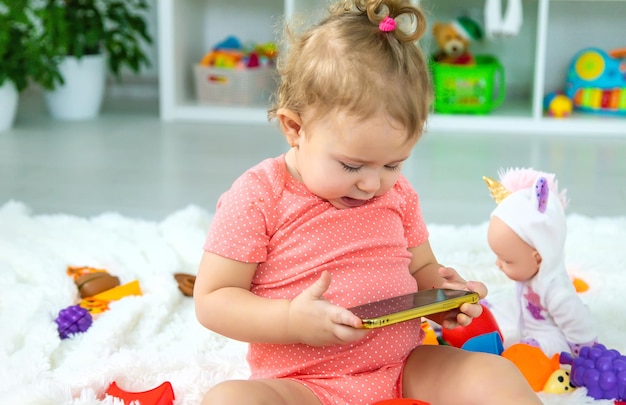 O bebê está jogando no telefone Foco seletivo