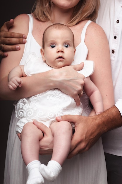 O bebê está sentado nos braços dos pais